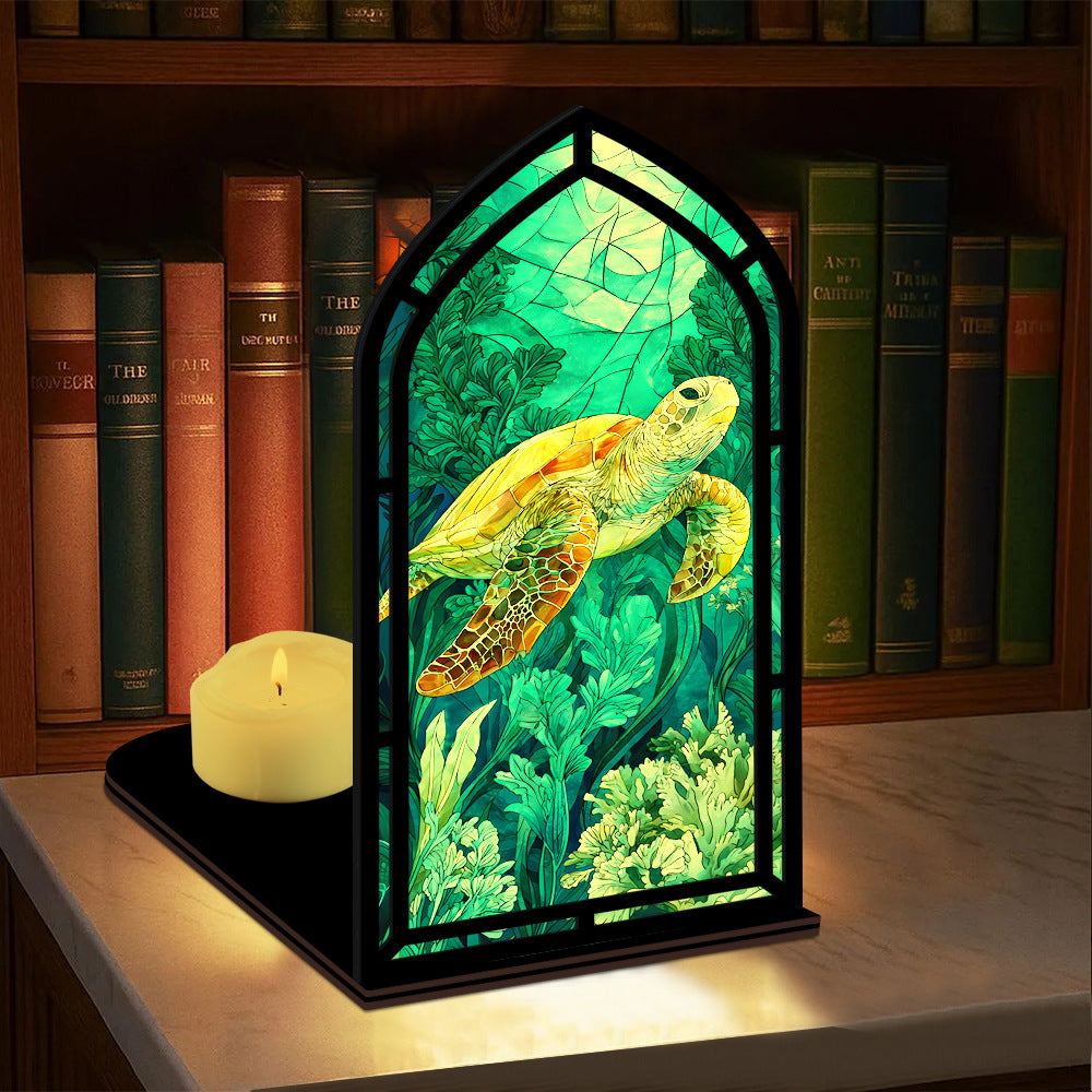 Book nook display with illuminated sea turtle panel, black base, and glowing candle beside it