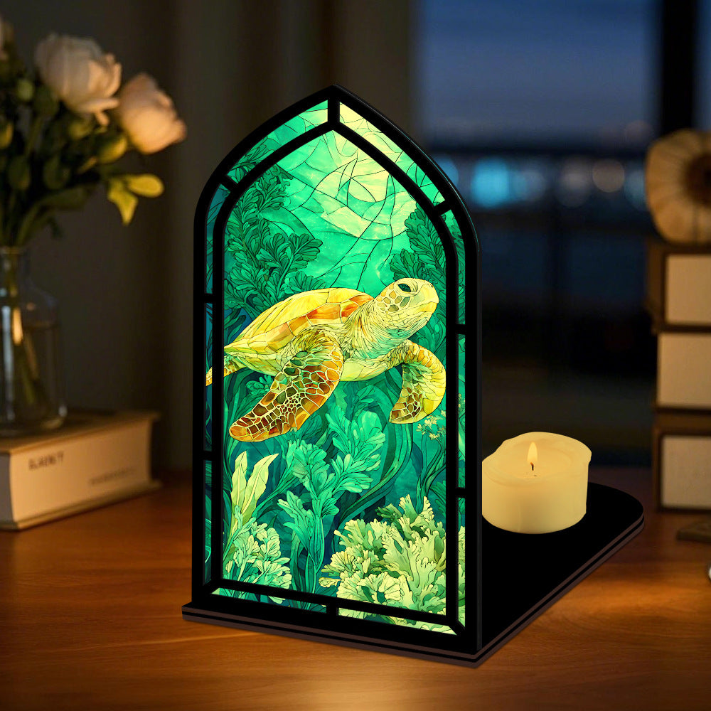 Book nook display with sea turtle illustration and green-lit glass panel, plus candle on base
