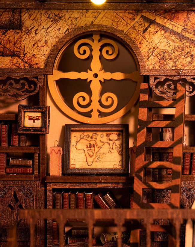 Mini book nook interior close-up with round wall emblem, framed map, and shelves
