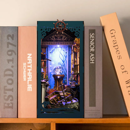 A miniature diorama of a ship's interior, featuring a ship's wheel, a treasure chest, and various other nautical elements, is displayed on a bookshelf.