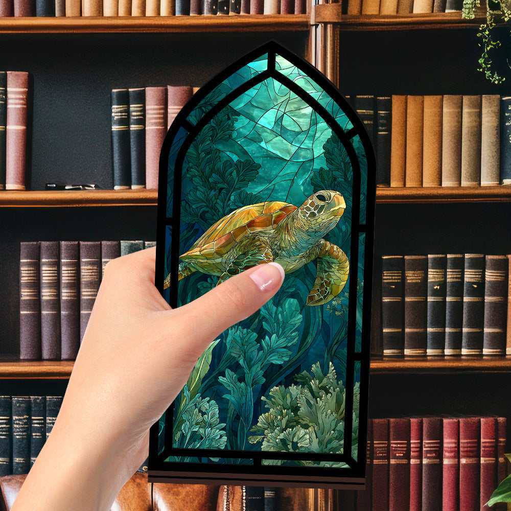 Book nook display with sea turtle artwork panel in a black arched frame, shown with hand