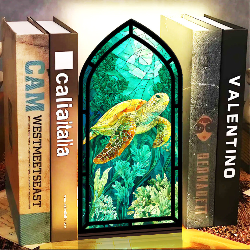Book nook display with sea turtle artwork in black arched frame, set between books