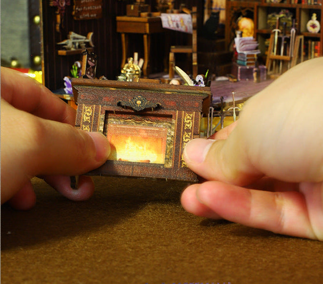 Hands placing a small lit drawer-like compartment on a miniature pirate desk