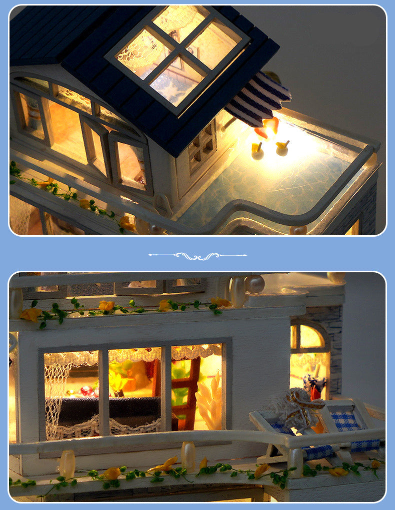 Close-up of blue-roof dollhouse with lit windows and warm interior details