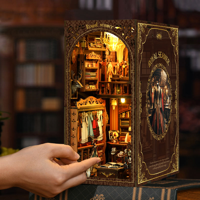 DIY book nook kit with glowing miniature interior and hand interacting with the panel