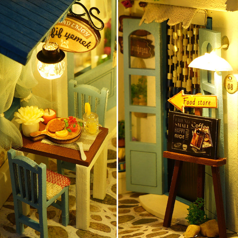 Miniature café table and shop sign with warm LED lights inside the book nook
