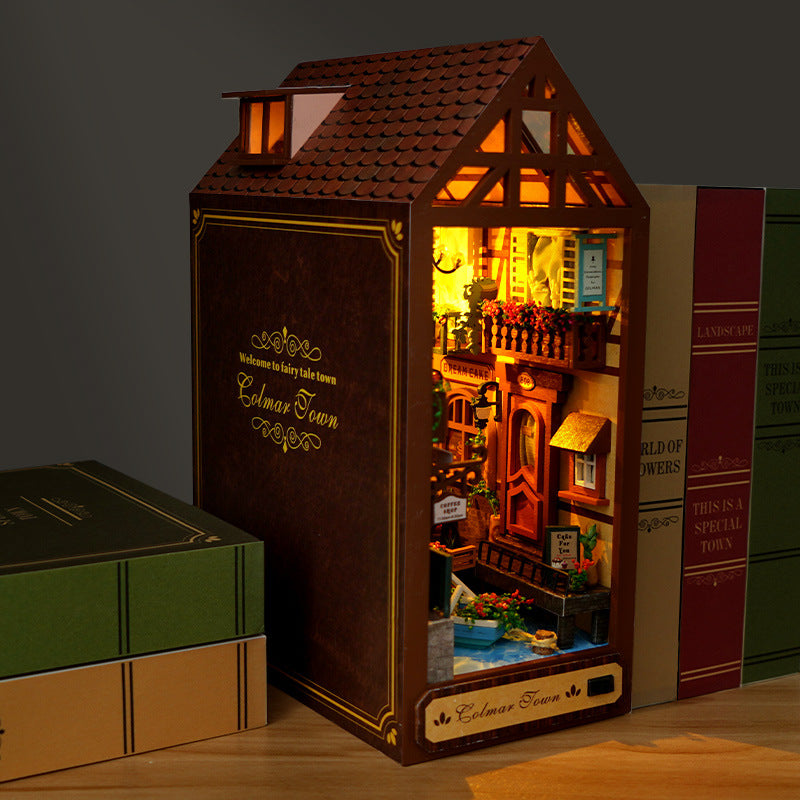 Miniature book nook house model with lit windows, balcony, and decorated entry