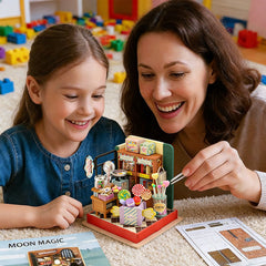 Miniature candy shop kit on table, child and adult assembling the lit wooden diorama
