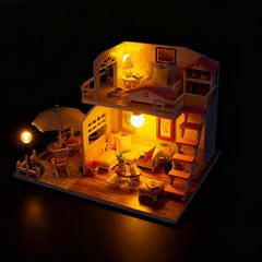 Miniature wooden dollhouse craft kit with warm light and furnished pink loft rooms