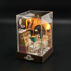 Light-up miniature bakery diorama kit with brick storefront, chairs, table, glass display base