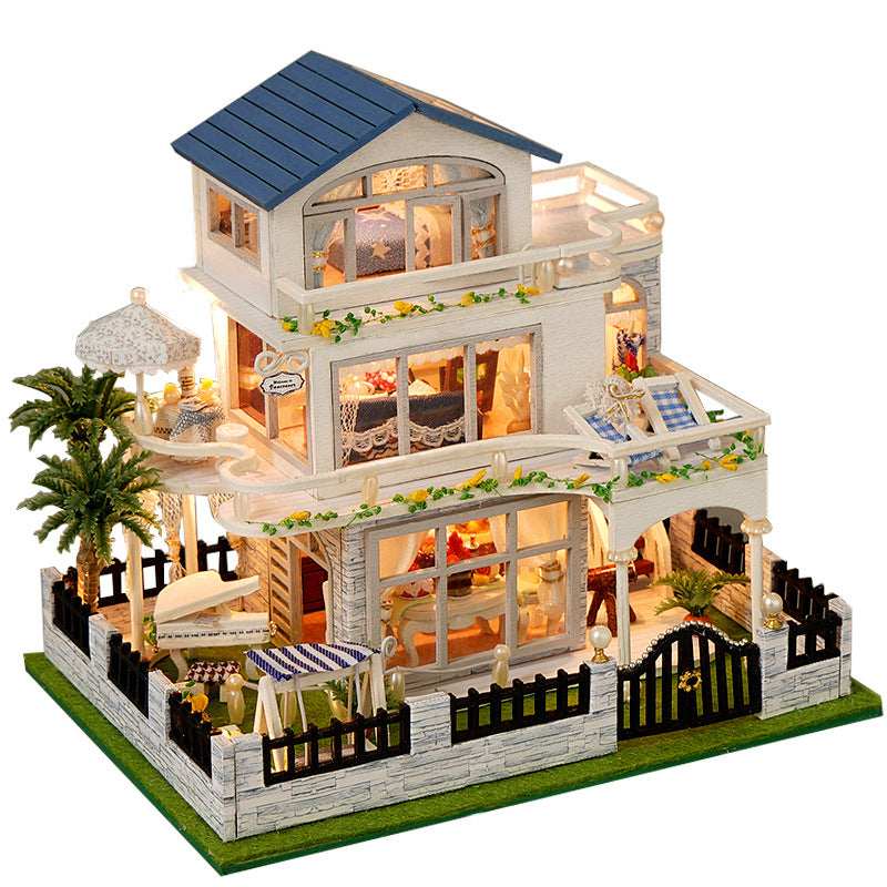 White miniature dollhouse with blue roof, covered patio, and fenced garden base