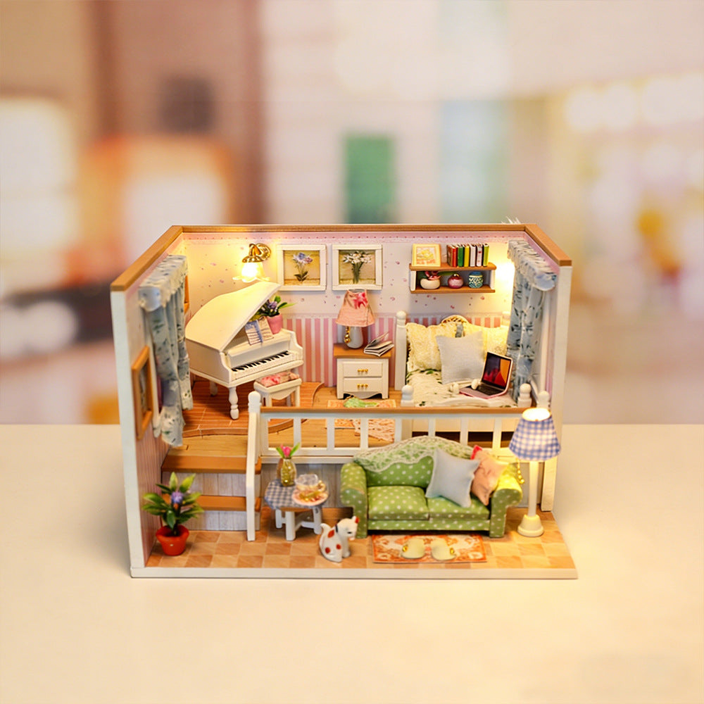 Miniature dollhouse room kit with green sofa, kitchen counter, bed, and lit floor lamp