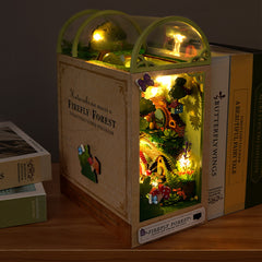Wooden DIY book nook kit on floor, glowing miniature forest scene through front window