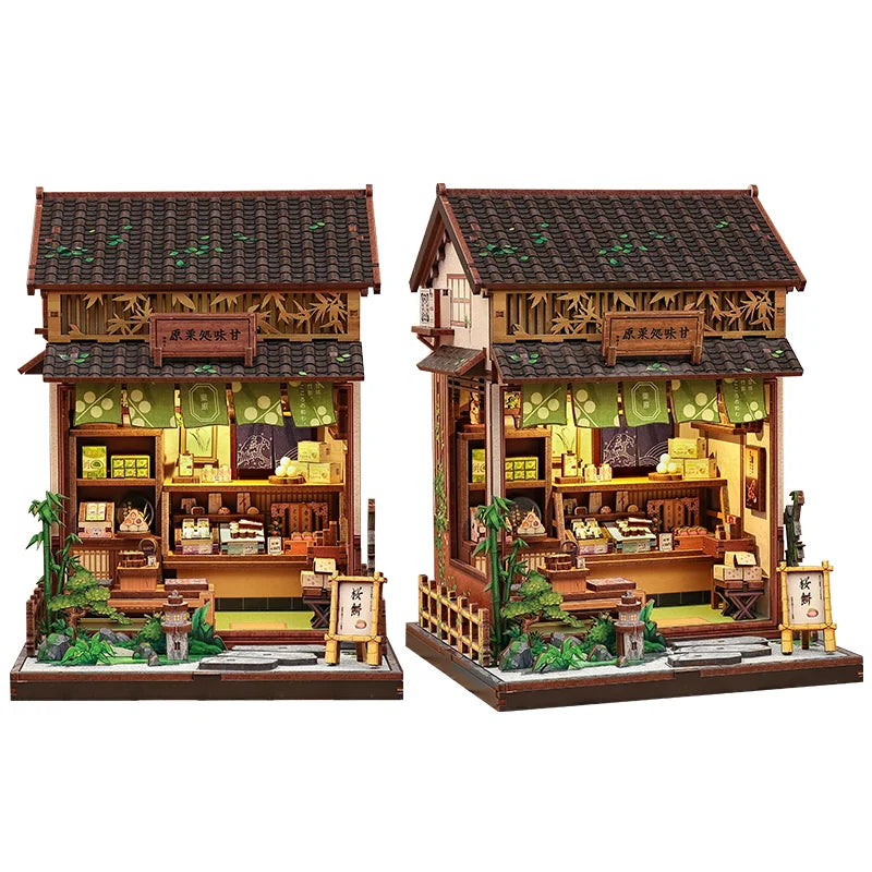 Green miniature wooden shop building with open front and warm interior, shown from two angles