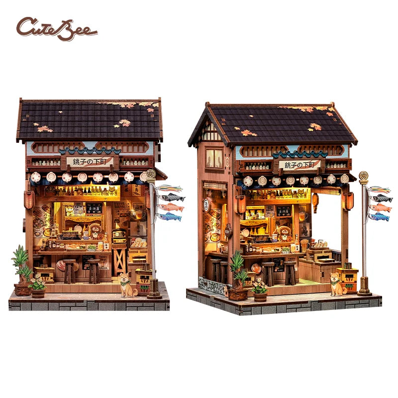 Wood-toned miniature shop building with warm-lit interior, tiled roof, and signage, two angles