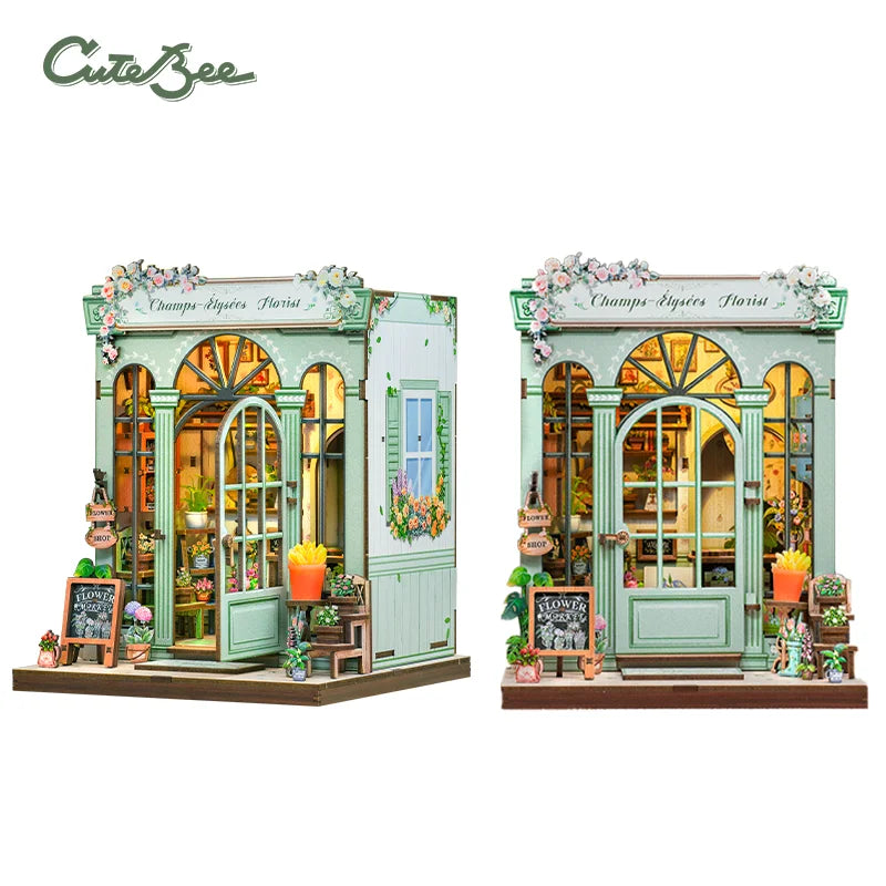 Mint-green miniature shop building with arched windows, flowers, and warm interior, two angles