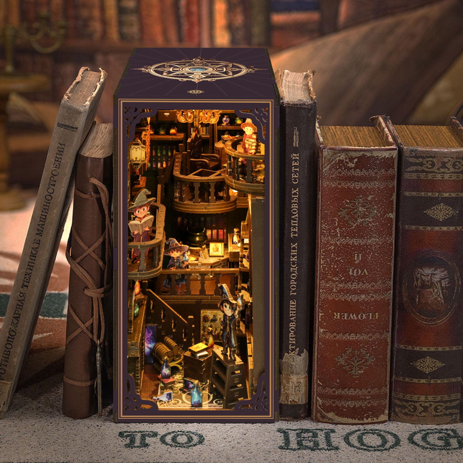 DIY book nook kit in front of books, showing lit miniature shelf room