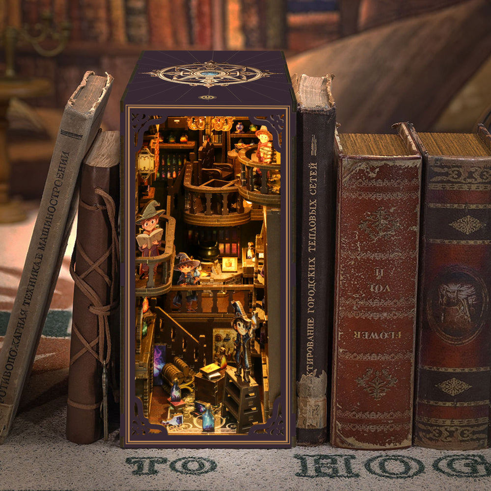 DIY book nook kit in front of books, showing lit miniature shelf room
