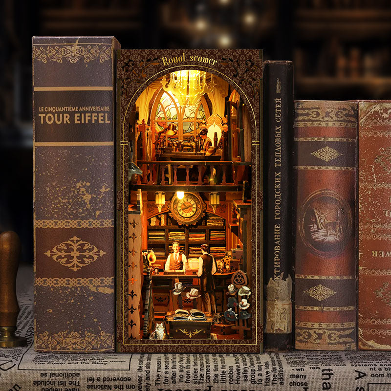A miniature diorama of a bookshop, featuring a small window on the bookshelf and a miniature figurine of a shopkeeper inside.