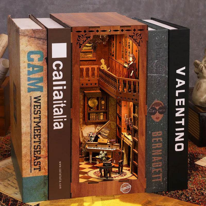 A miniature wooden dollhouse is displayed between two large books, one titled "CAM WESTMEET SEAST" and the other "BERNADETO".