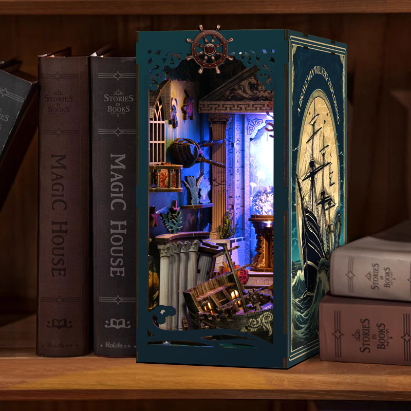 A miniature diorama of a ship's interior is displayed on a bookshelf, surrounded by other books.