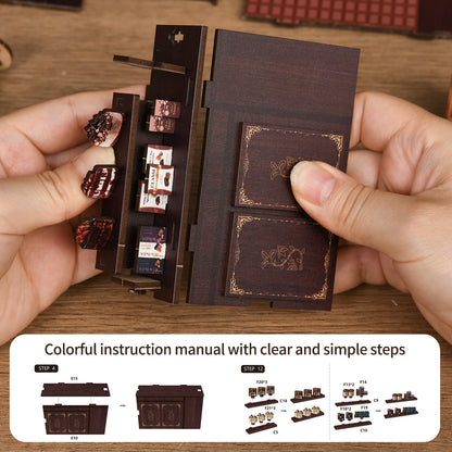 A person's hands holding a small wooden box with various items inside, including what appear to be small figurines or knick-knacks. The box has a clear instruction manual with step-by-step guidance on how to assemble or use the box.