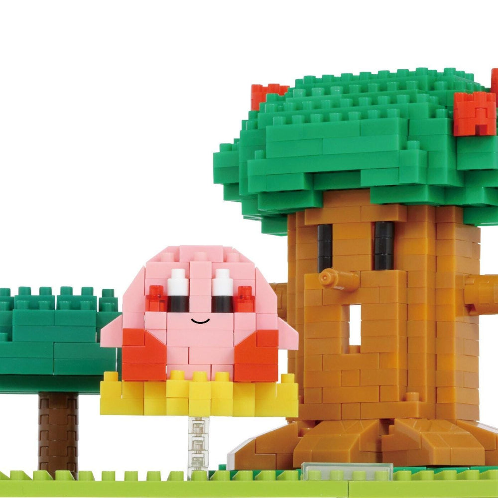 Close-up of assembled nano blocks Kirby figure beside green leafy tree trunk