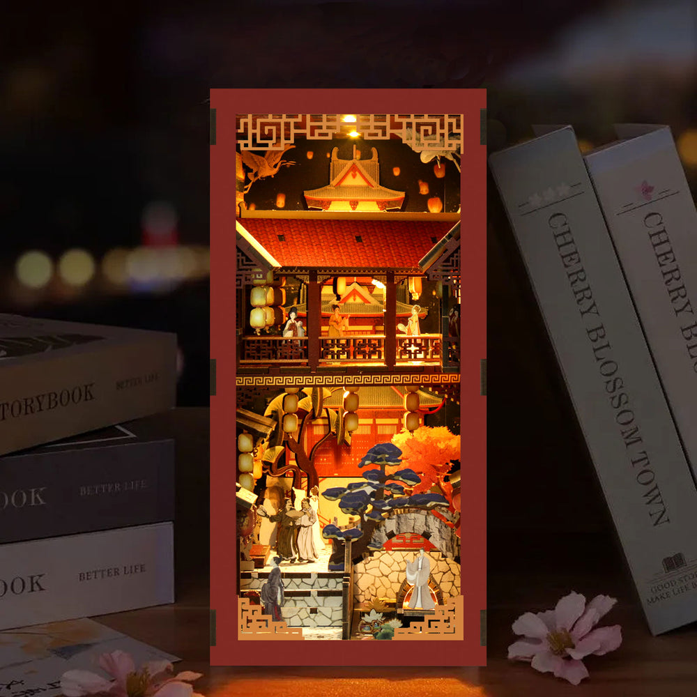DIY book nook kit box with red and gold lit interior scene, near gray book spines