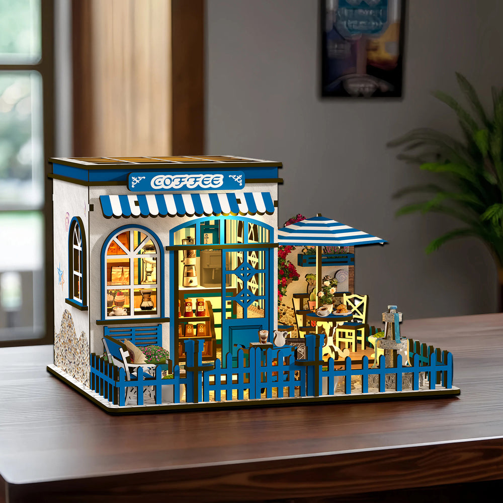 DIY miniature coffee shop house kit on table, blue storefront, striped awning and patio set