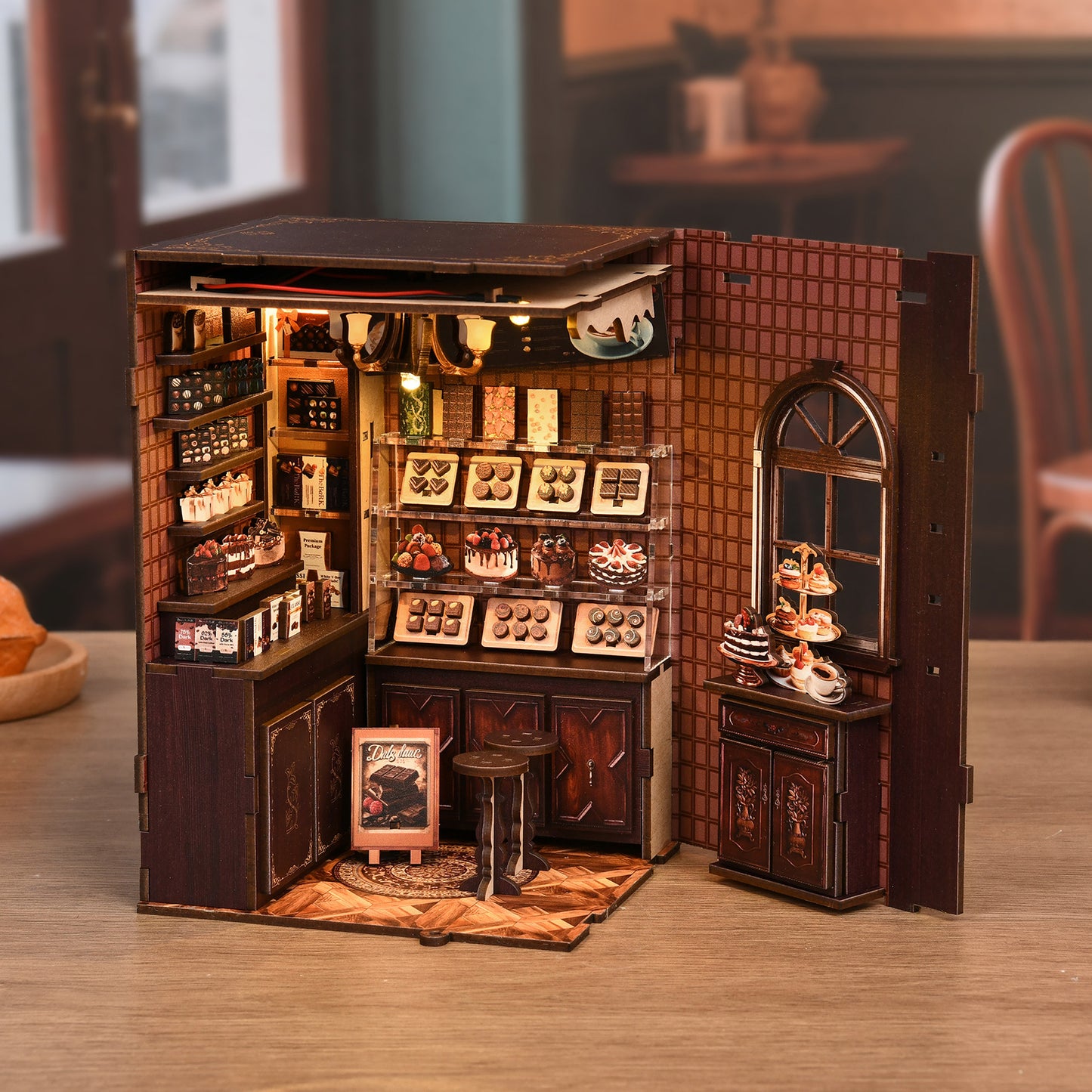 A miniature model of a chocolate shop, featuring a display of various chocolate products and a small window.