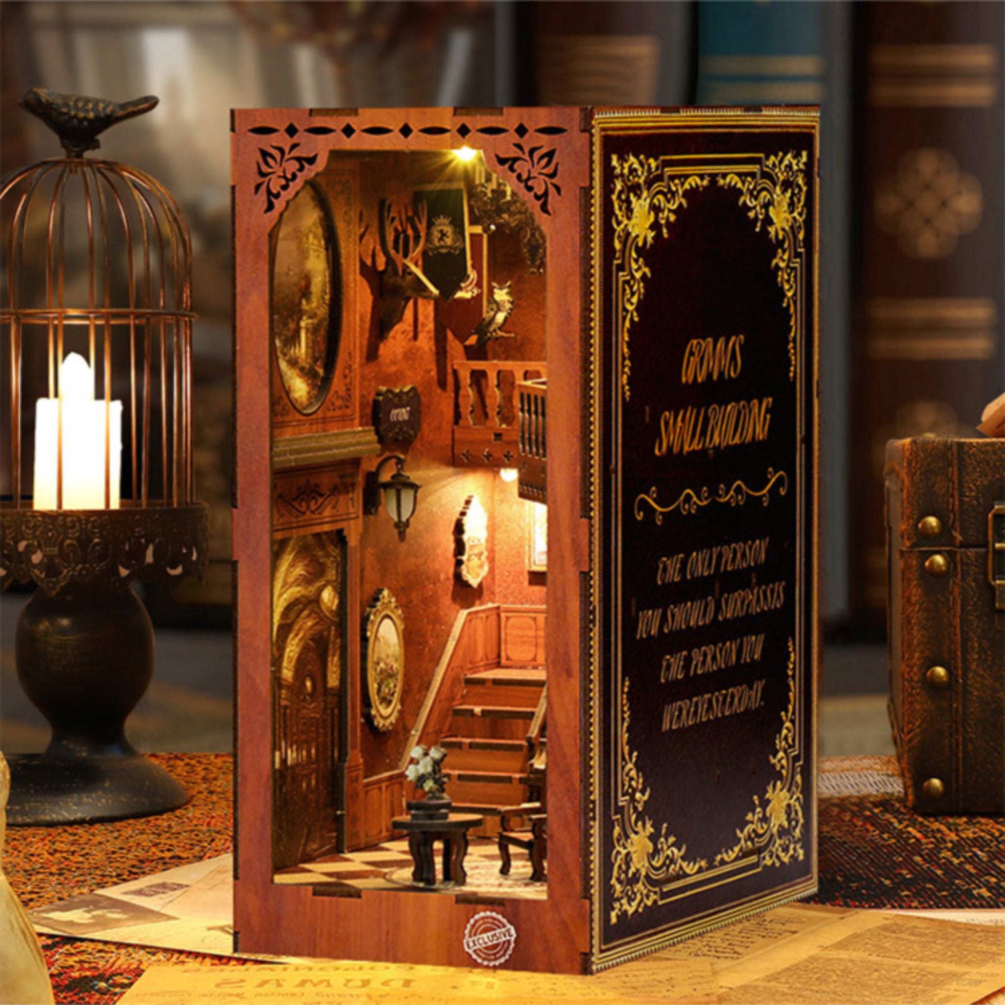 Book nook kit display with side panels, revealing a lit miniature room with stairs and table