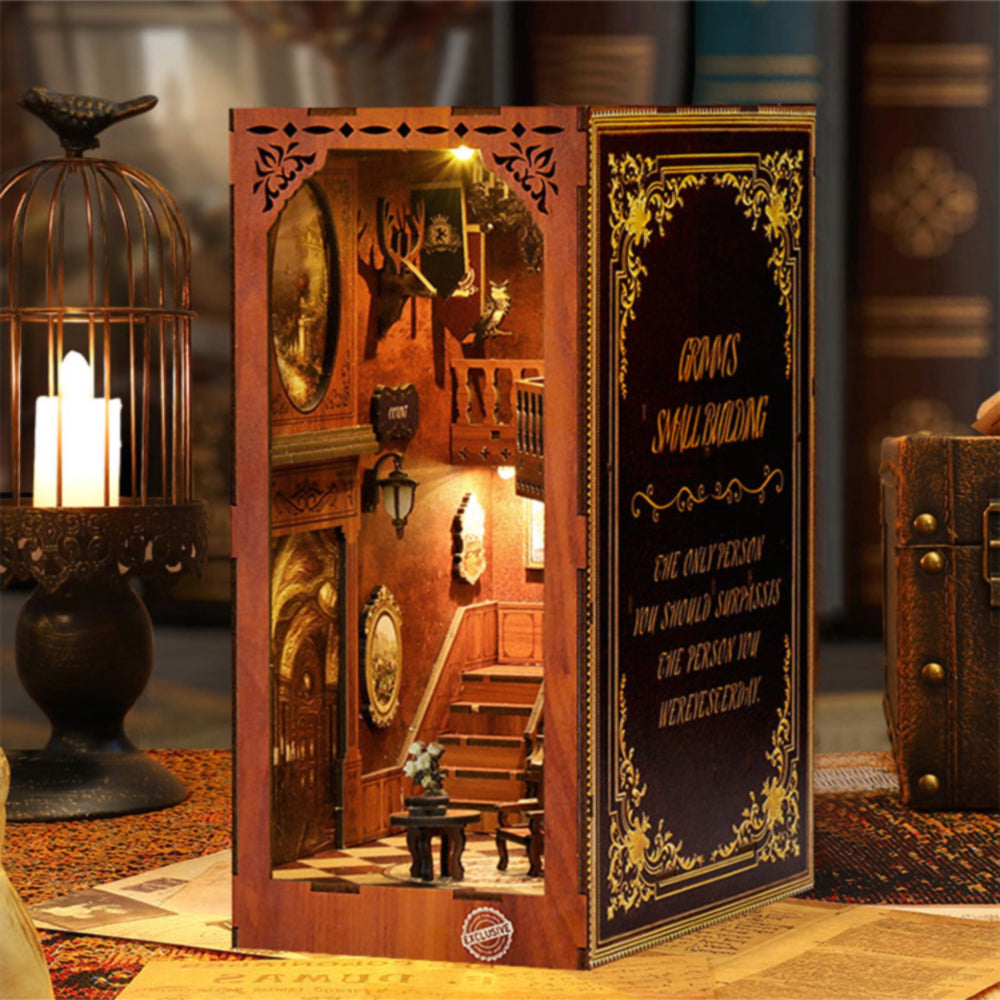 Book nook kit display with side panels, revealing a lit miniature room with stairs and table