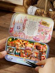 Miniature candy shop diorama in a small open metal tin held by hands