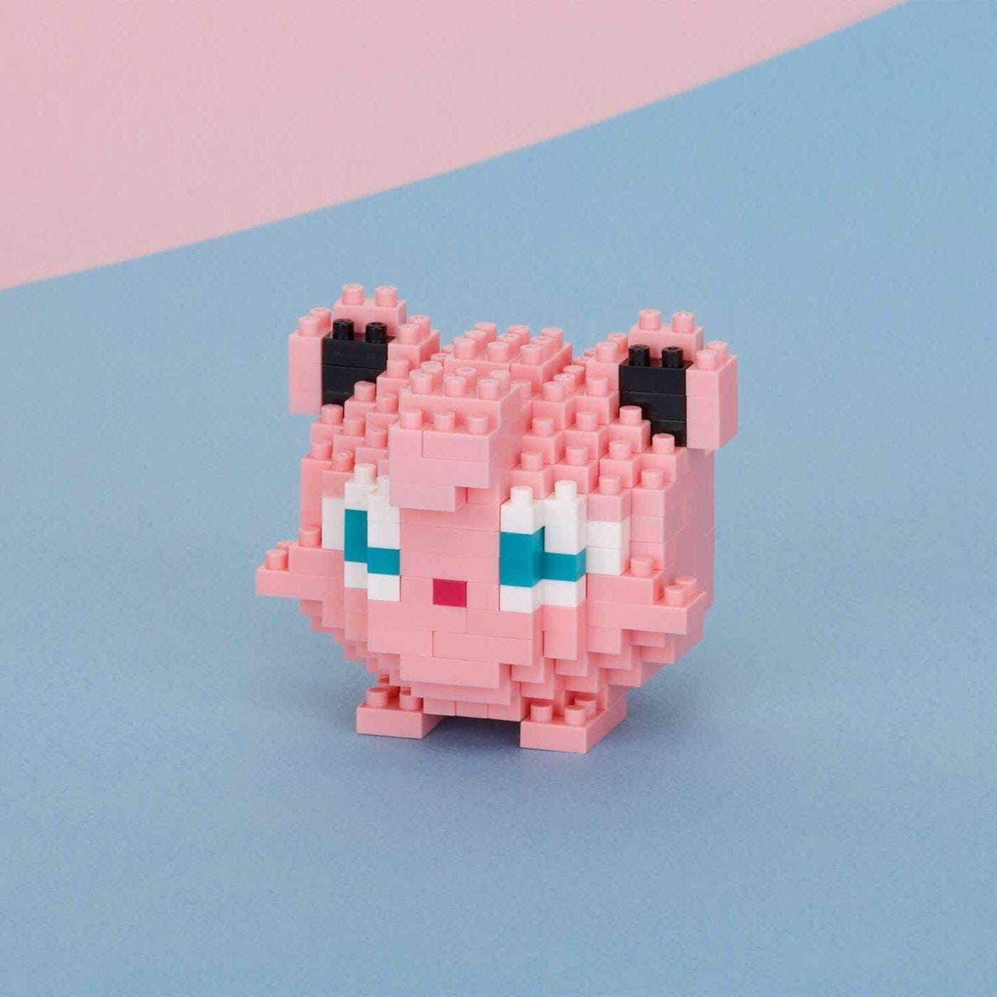 A pink pixelated character resembling a small animal or creature, composed of numerous small blocks, is the main focus of the image.