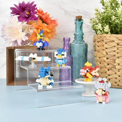 a collection of colorful pixel art toys, including a blue bird, a pink and yellow fish, and a blue and white robot, arranged on a shelf or display.