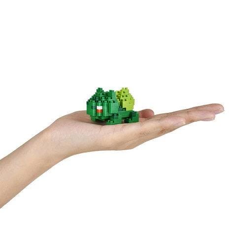 A hand holding a small green toy in the palm.