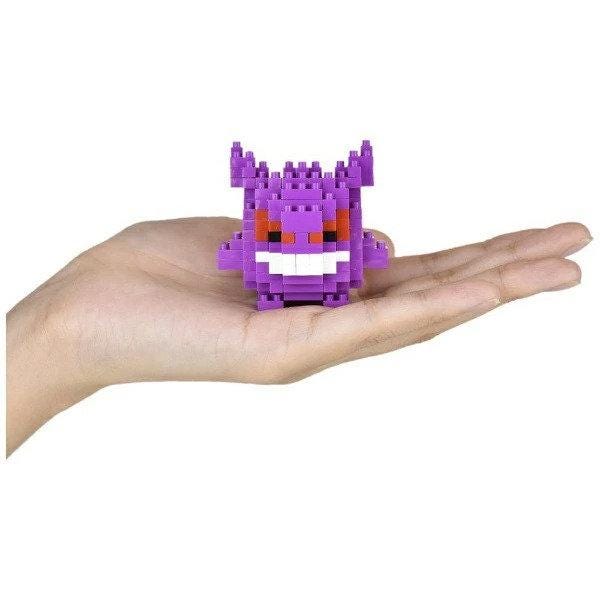 A hand holding a small, purple, pixelated character resembling a Pokémon.