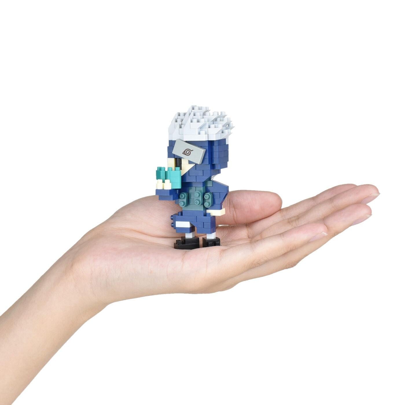 A hand holding a small, colorful, and intricate toy figure made of small building blocks.