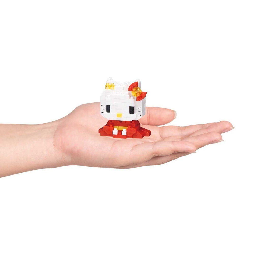 A hand holding a small white Hello Kitty figurine against a white background.