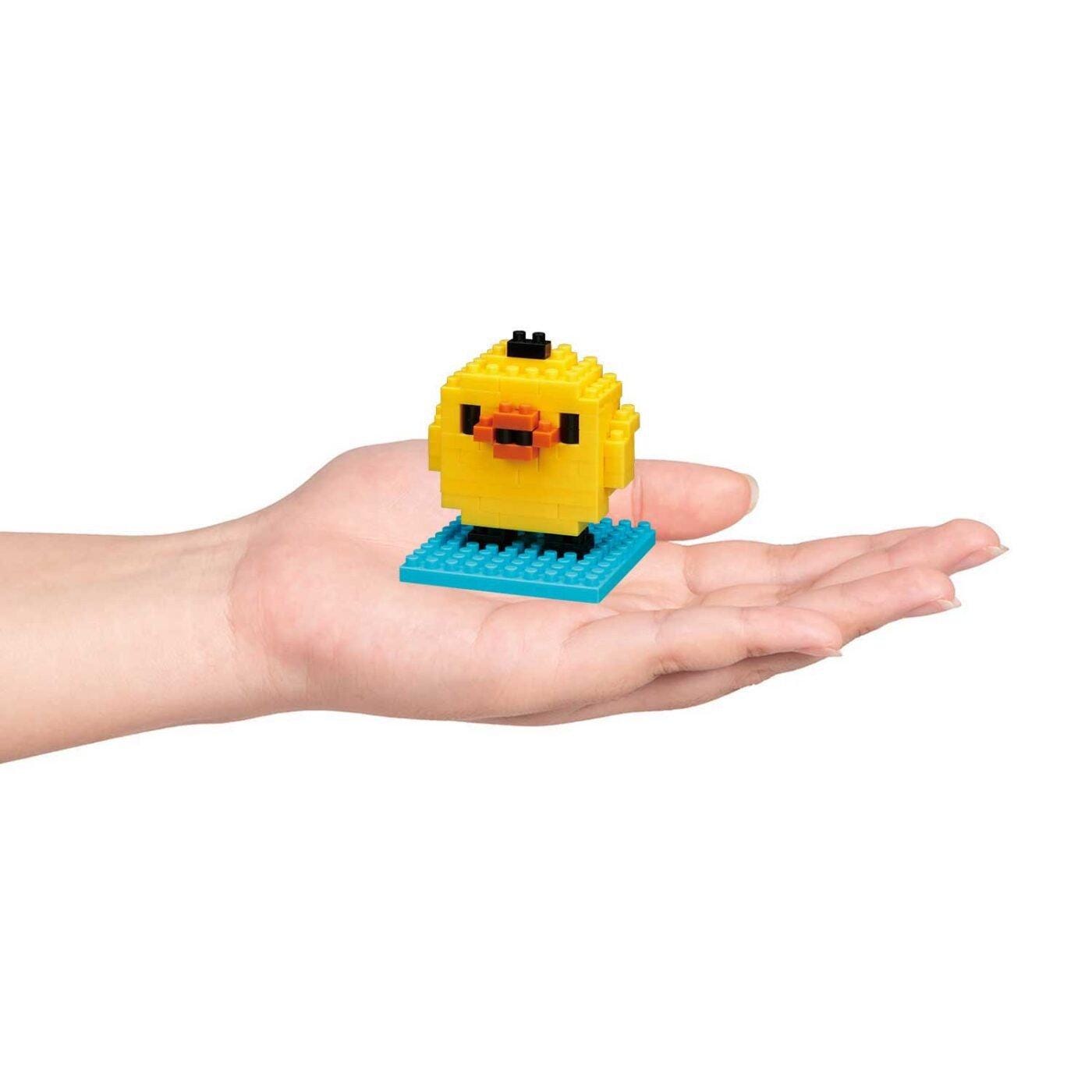 A hand holding a small yellow bird-shaped object made of small, colorful blocks.