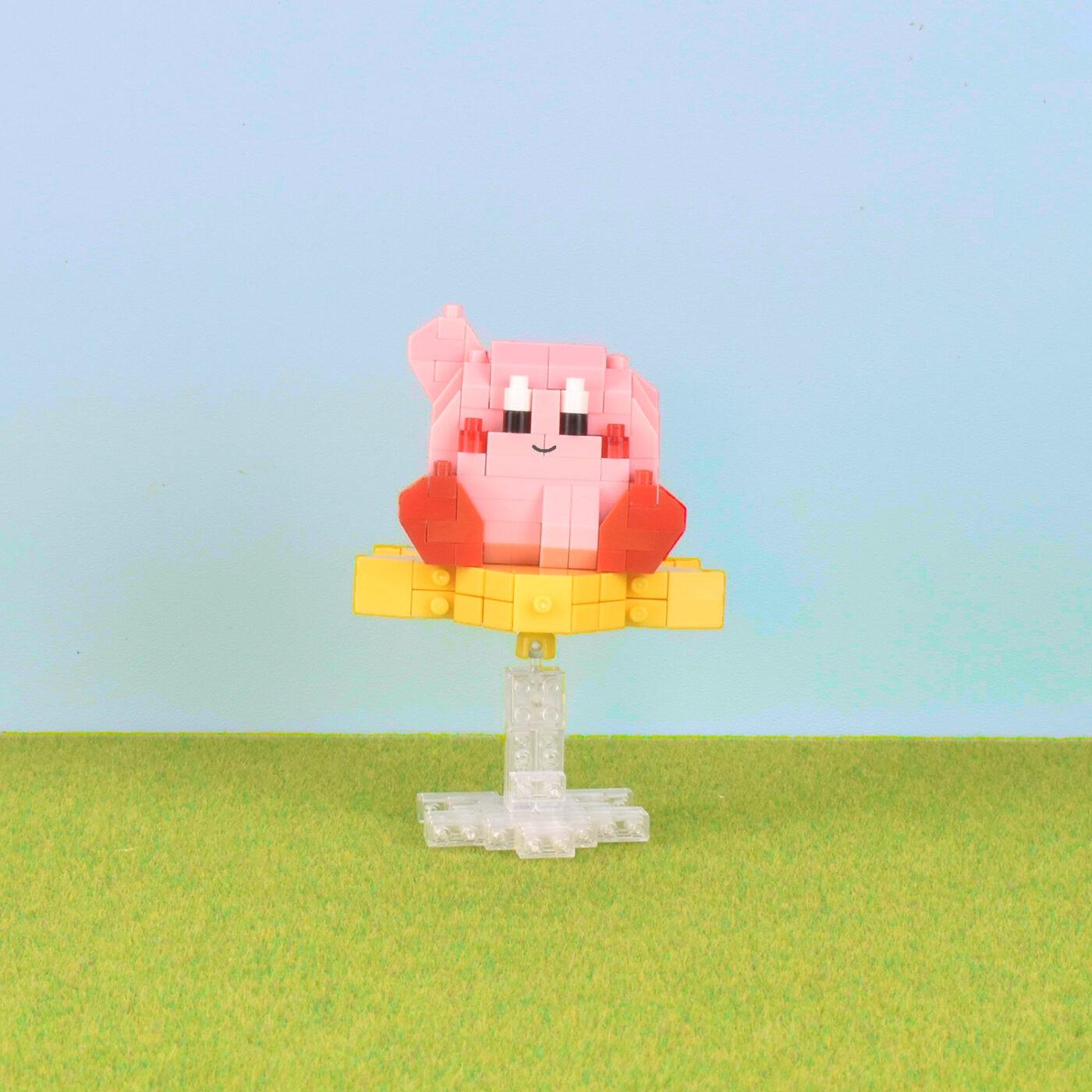 A pink, pixelated character resembling a character from a video game stands on a yellow base against a blue background.