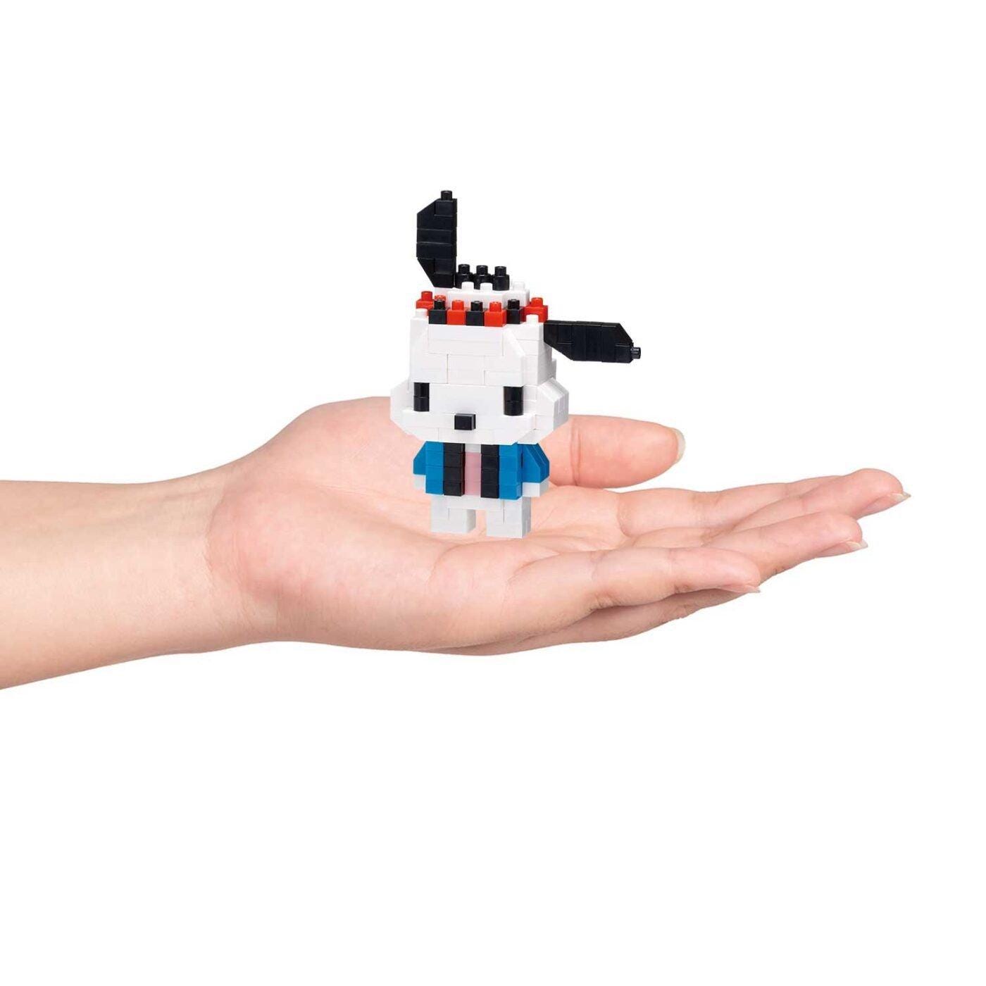 A hand holding a small, white and blue pixelated character.