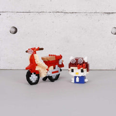 two small, colorful, and whimsical objects, including a red and white motorcycle-like vehicle and a Hello Kitty-style character, sitting on a gray surface against a white background.