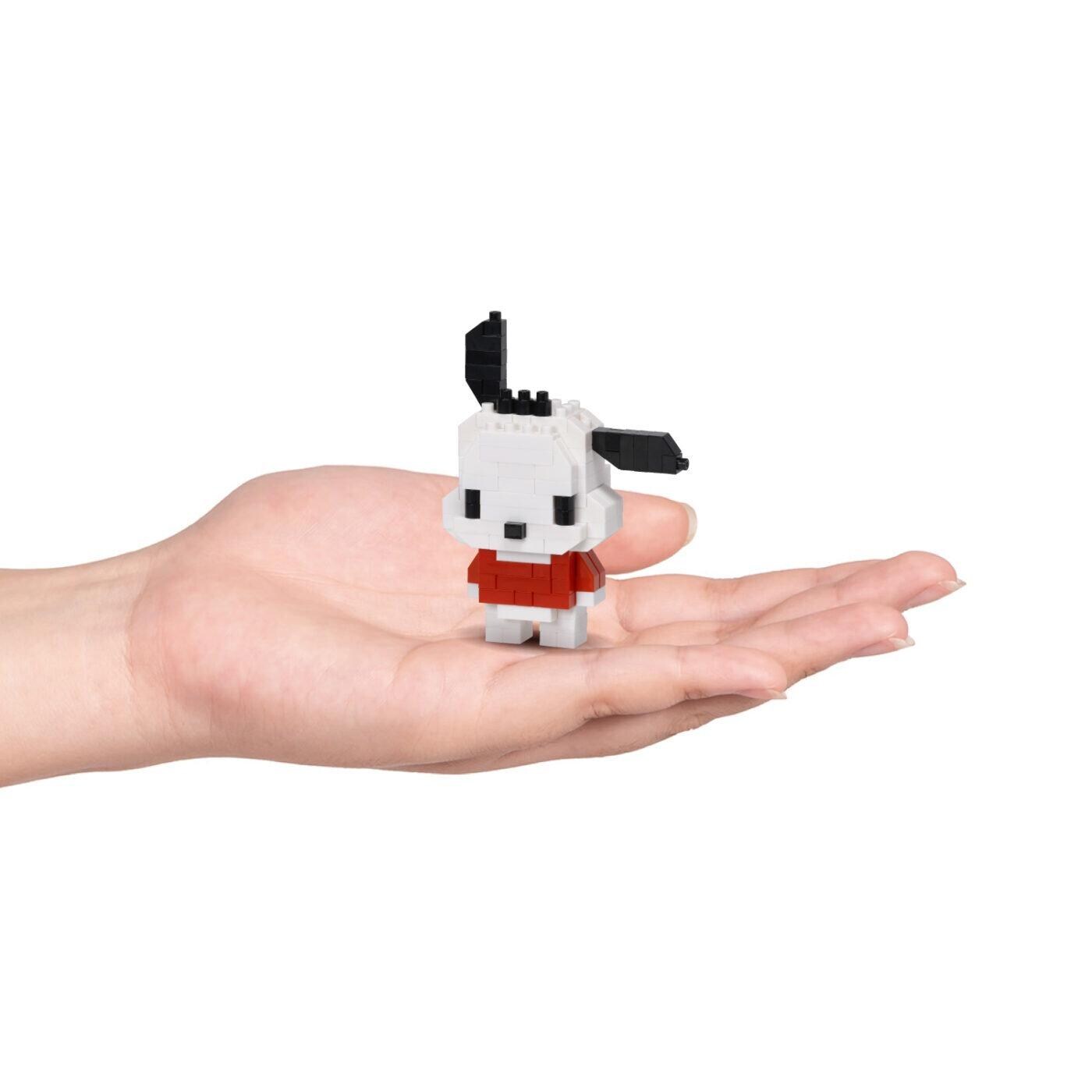 A small, white, pixelated dog figurine is being held in a person's hand against a white background.