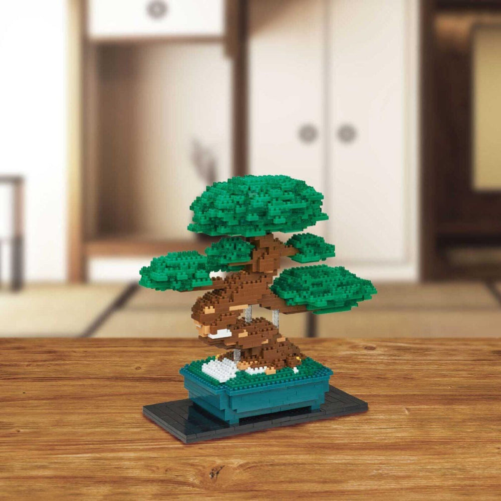 A small, intricately crafted bonsai tree made of small, colorful building blocks is displayed on a wooden surface.