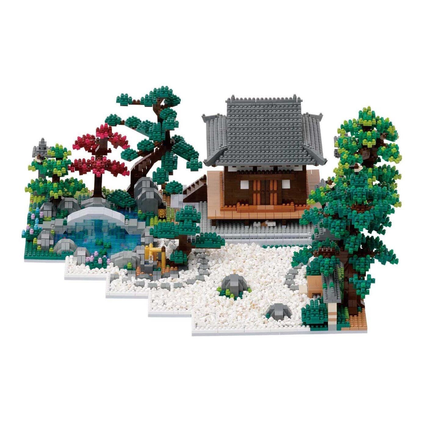 A detailed model of a Japanese-style house surrounded by a garden, featuring various elements such as trees, rocks, and a pond.