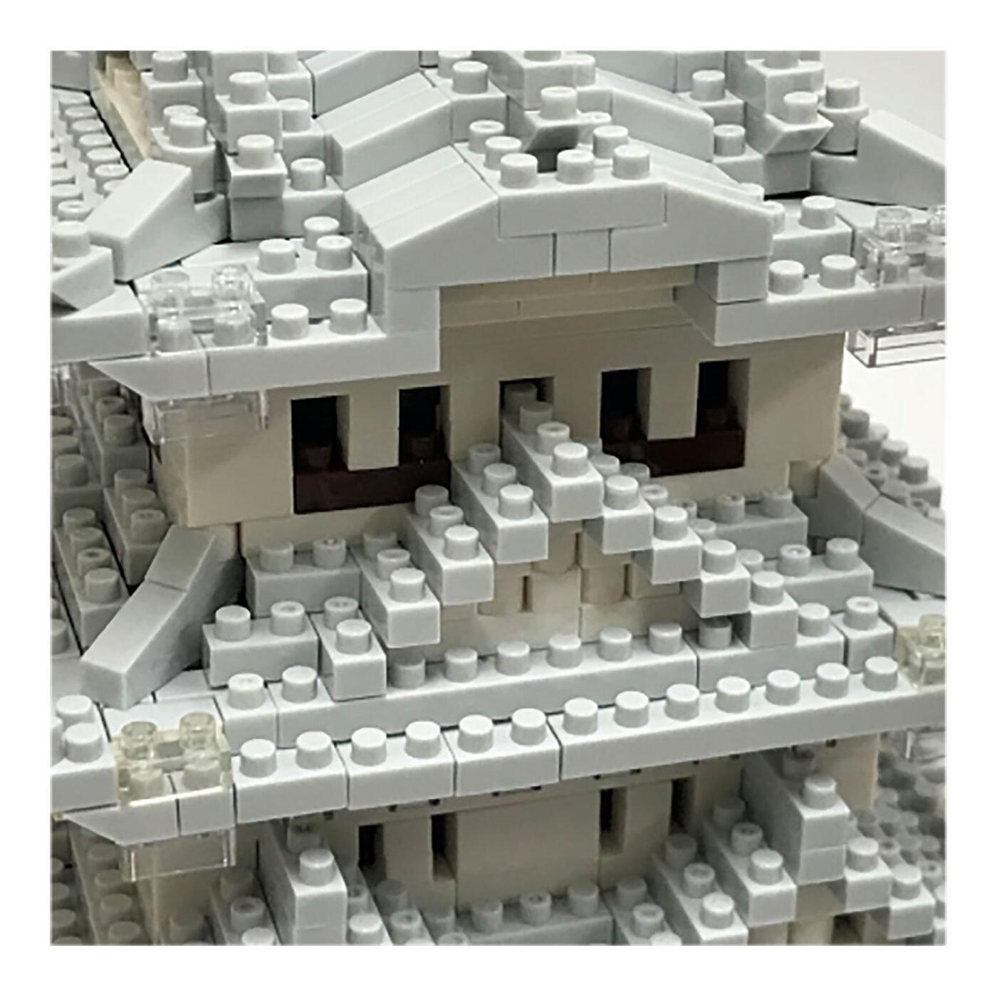 A close-up view of a complex, intricate structure made of numerous small white and gray building blocks, resembling a Lego or similar construction toy.