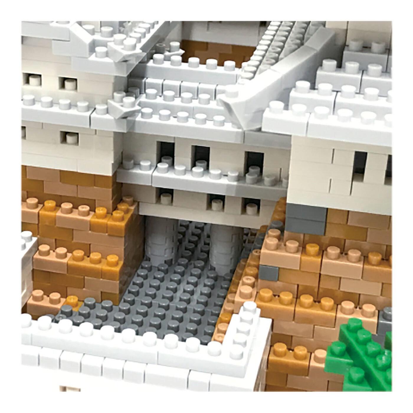 A detailed 3D model of a building constructed from numerous small white and gray Lego bricks, with a green Lego tree visible on the right side.