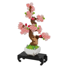 A pink flower arrangement made of small, colorful building blocks, resembling a bonsai tree.
