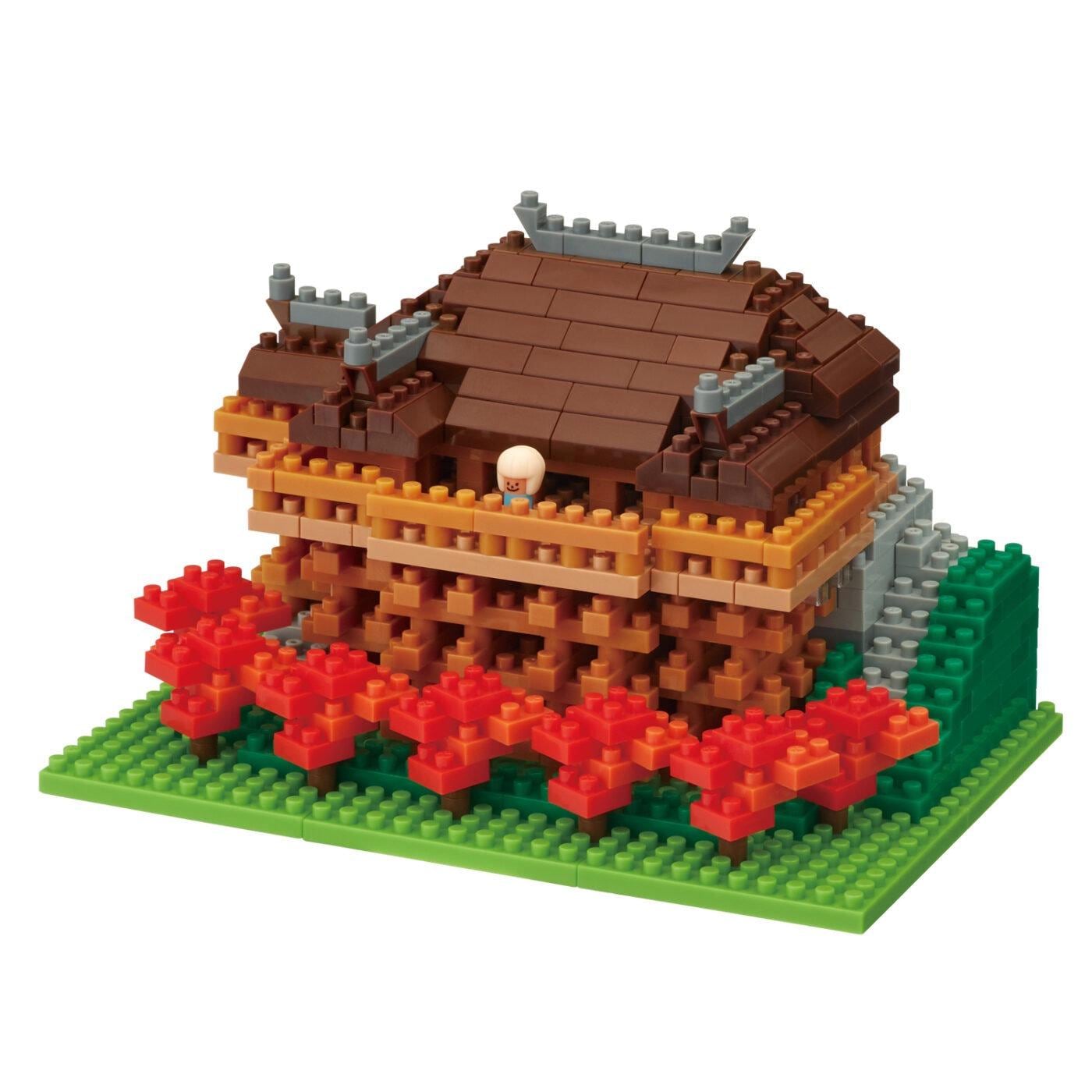 A colorful, intricate model of a house made of small building blocks, with a small figure of a person on top.